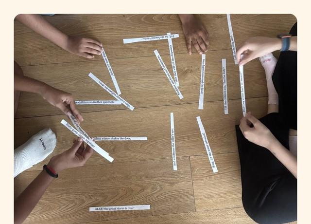 Children rebuilding a poem from paper strips on the floor